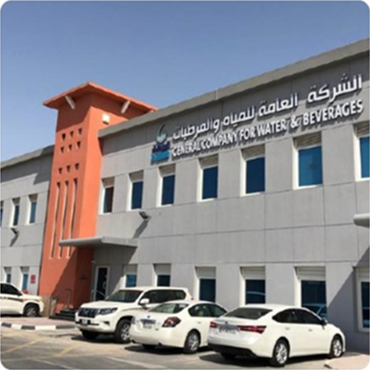 xterior view of a long, low-rise commercial or office building with numerous windows and parked cars in front.