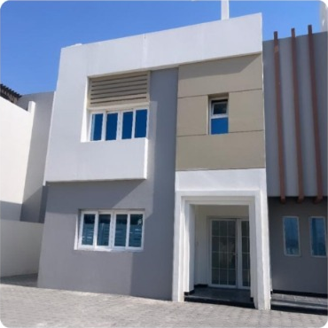 Exterior view of a modern, minimalist two-story house with large windows and a flat roof.